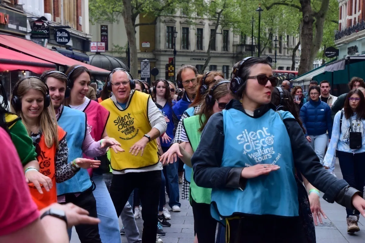 A group of people on a London street wearing different coloured tabards and headphones. 