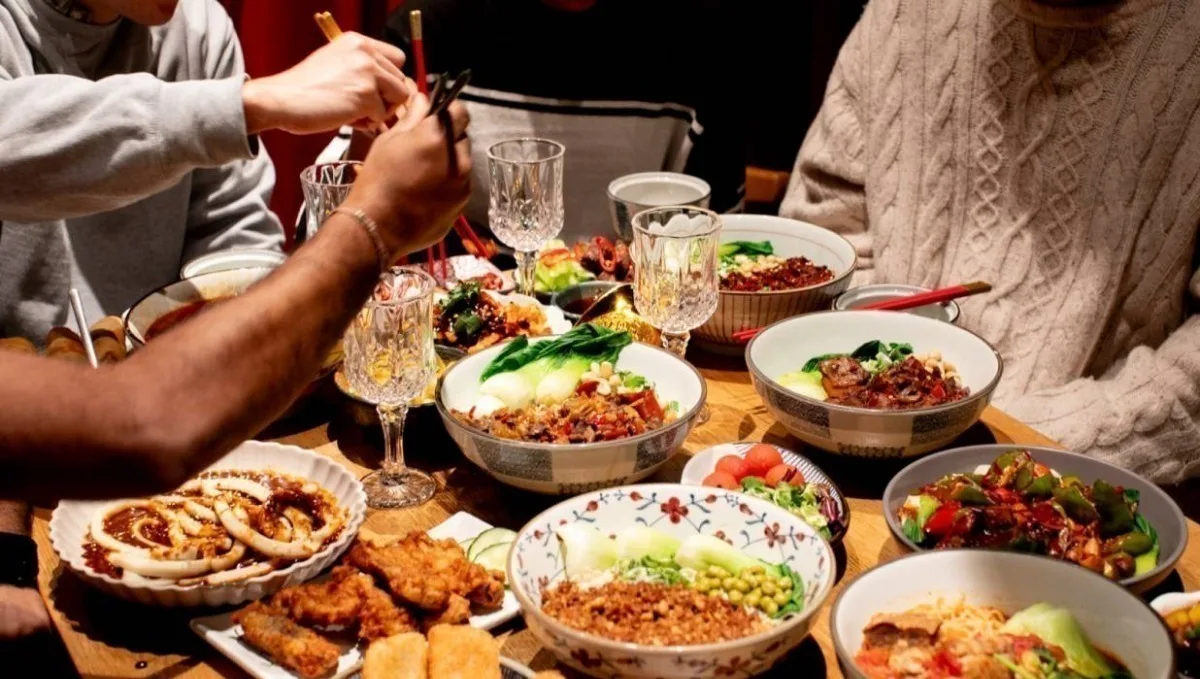 A table covered in many East Asian dishes and wine glasses.