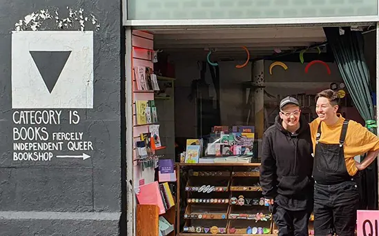2 white women standing in the large open doorway of a shop, next to a sign that reads "CATEGORY IS BOOKS: FIERCELY INDEPENDENT QUEER BOOKSHOP".
