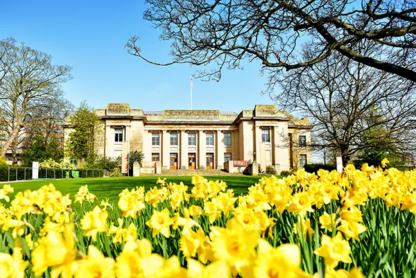 A museum on a lawn with daffodils in front. 