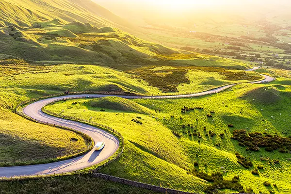 Steep rolling green hills with a winding road going across the middle. 