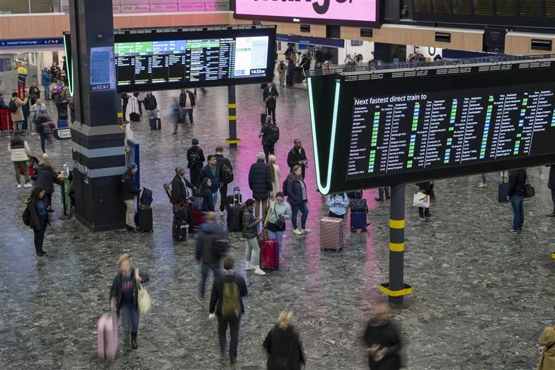 London Euston station concourse with passengers checking departure boards and walking with luggage.