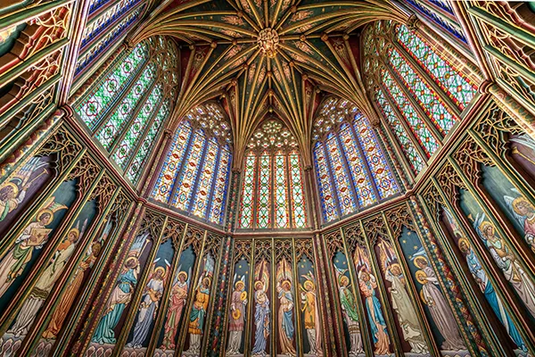 Inside an octagonal church tower with dazzling stained glass panels and gold columns. 