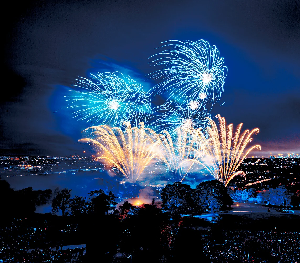 Blue and orange fireworks exploding in the night sky above London. 