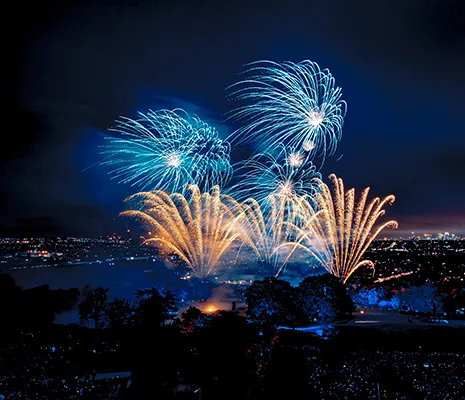 Blue and orange fireworks exploding in the night sky above London. 