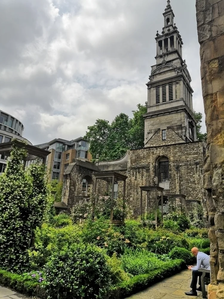 A pocket-sized walled park in London with an old church behind. 