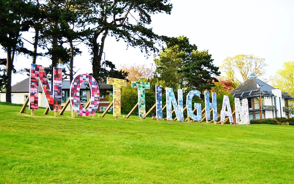 Large colourful wooden letters spelling NOTTINGHAM on a green lawn. 