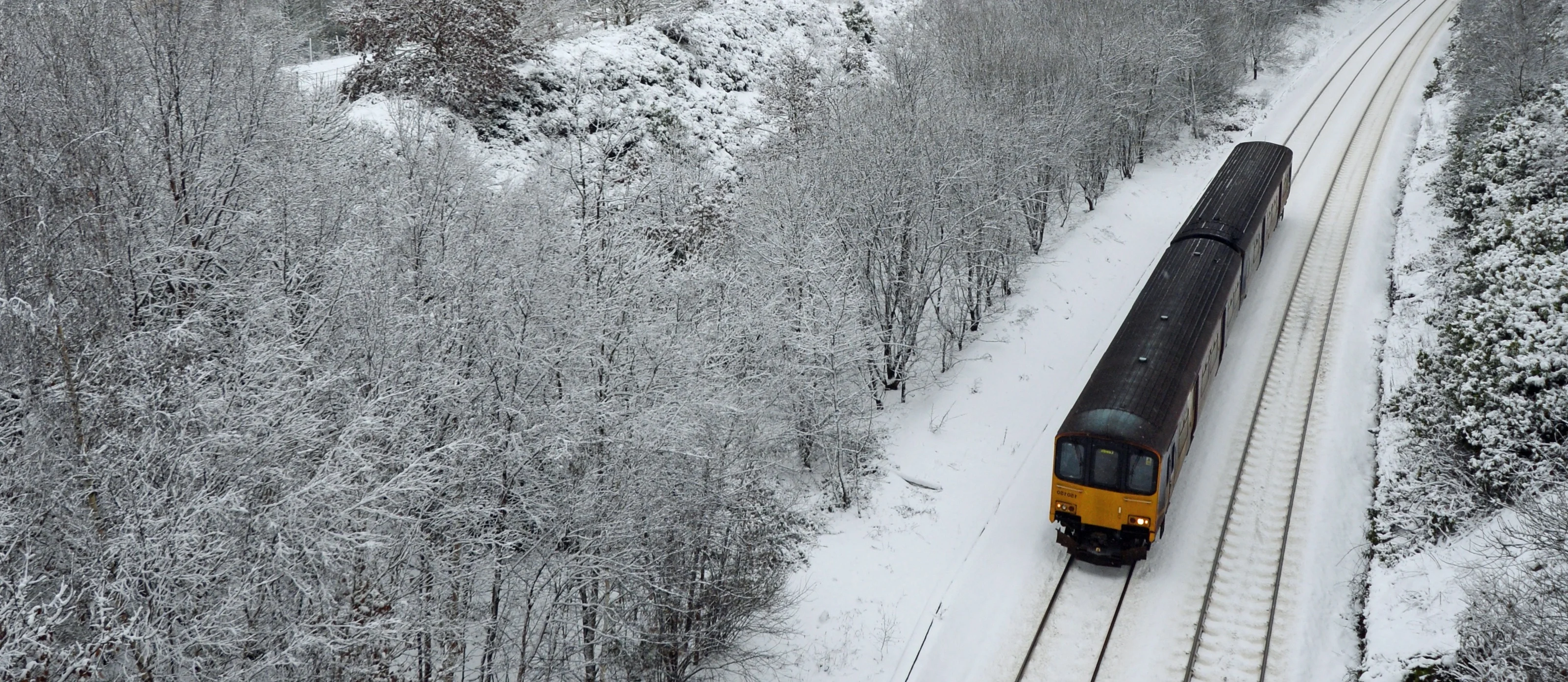 A train moving along a snowy track with snow-covered trees on both sides