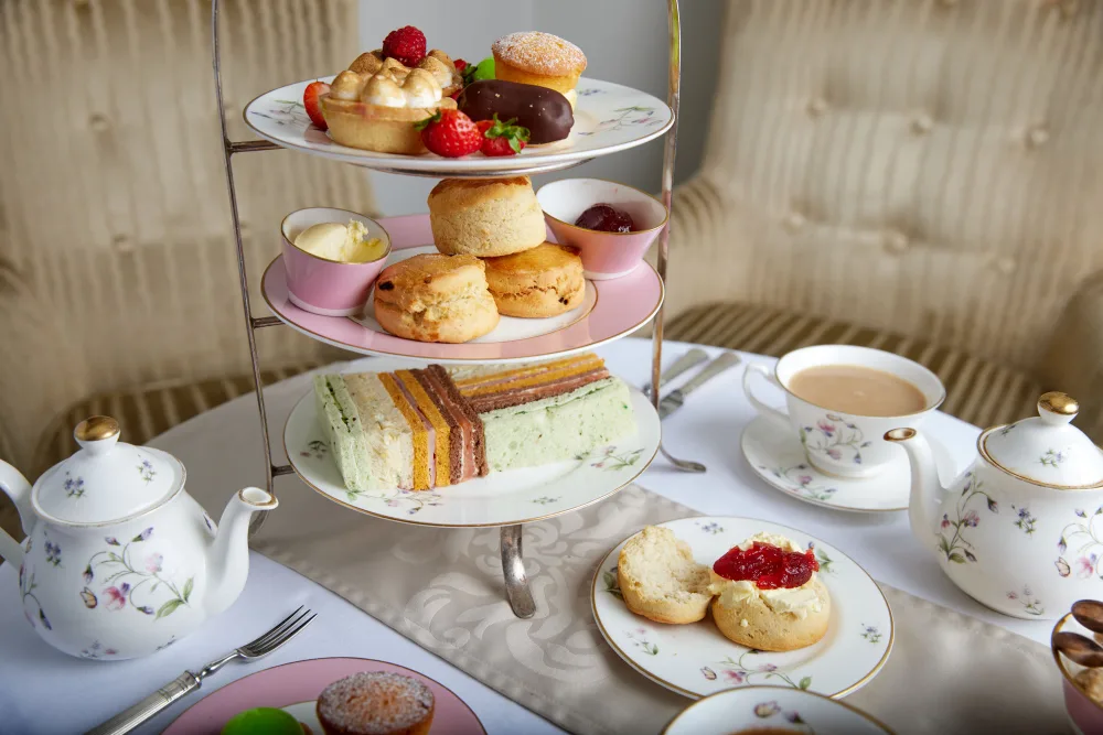 A hotel table set with afternoon tea, sandwiches and cakes