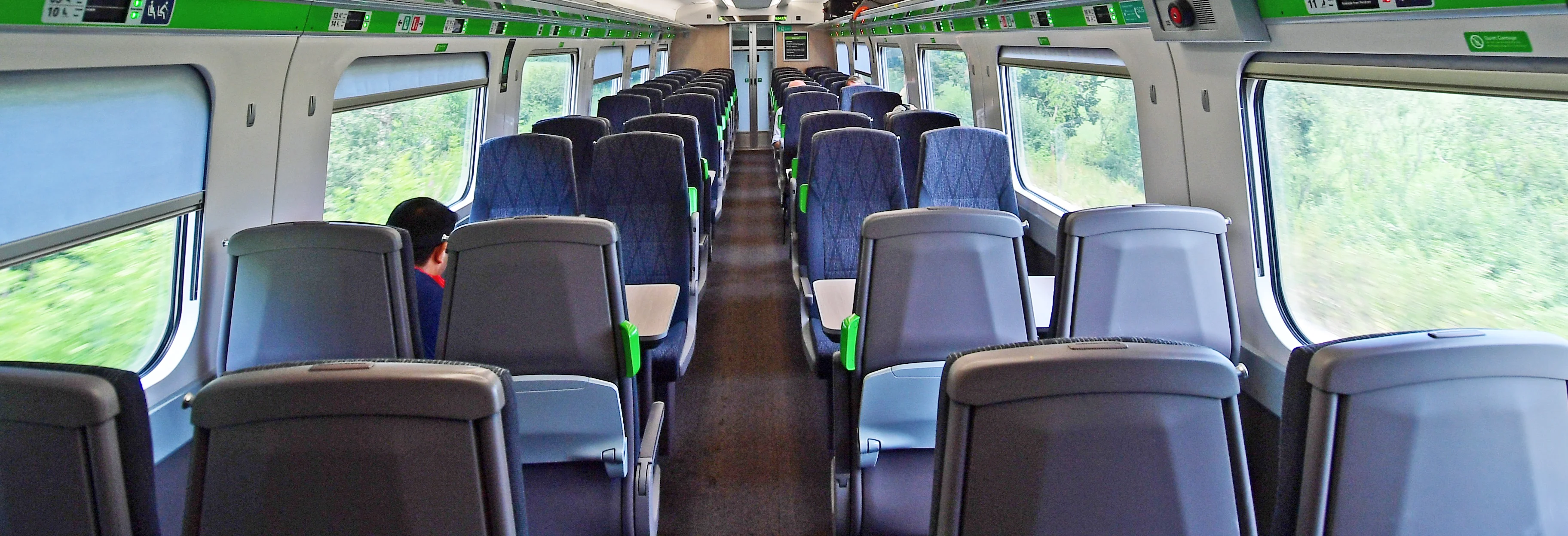 A train carriage with a number of empty seats showing green lights for unreserved seating