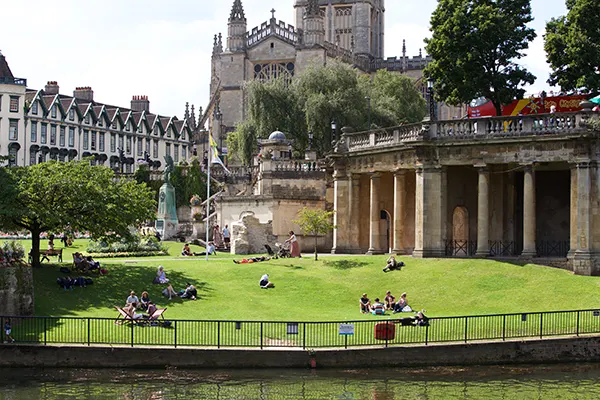 People sitting on the lawn in front of a historic abbey building. 