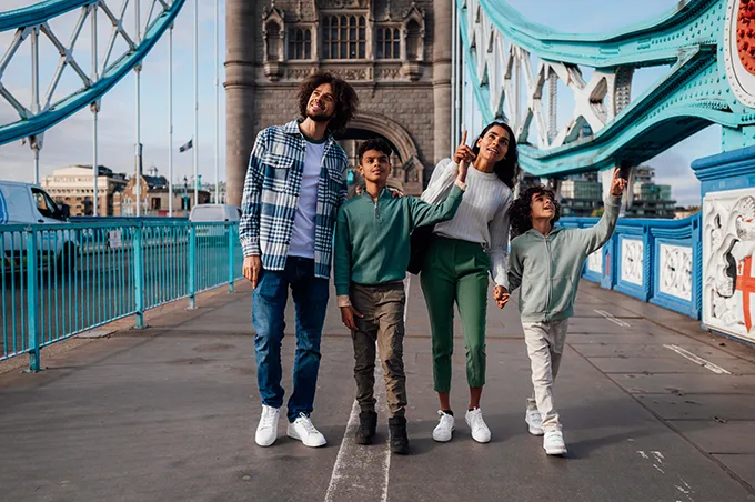 A mother and father and 2 young boys walking across Tower Bridge.
