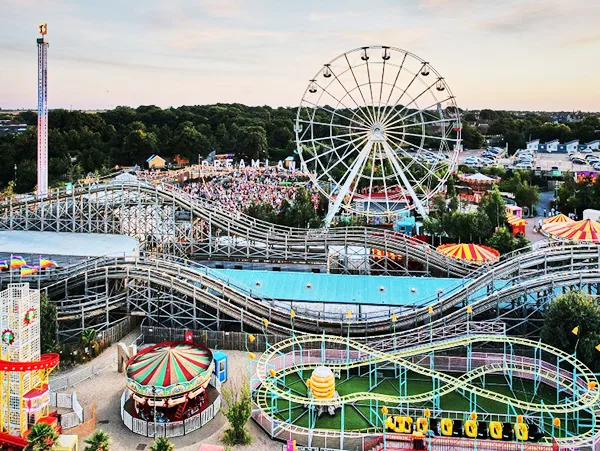 Aerial view of a funfair with a ferris wheel, roller coasters and other rides. 