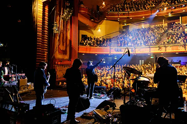 View from the stage of a traditional theatre with a band playing and looking out at the audience.