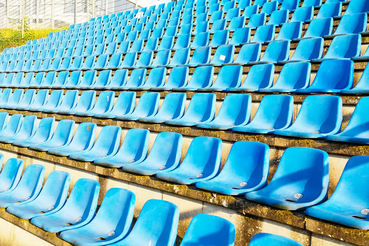 Rows of empty blue plastic seats at a sports stadium. 