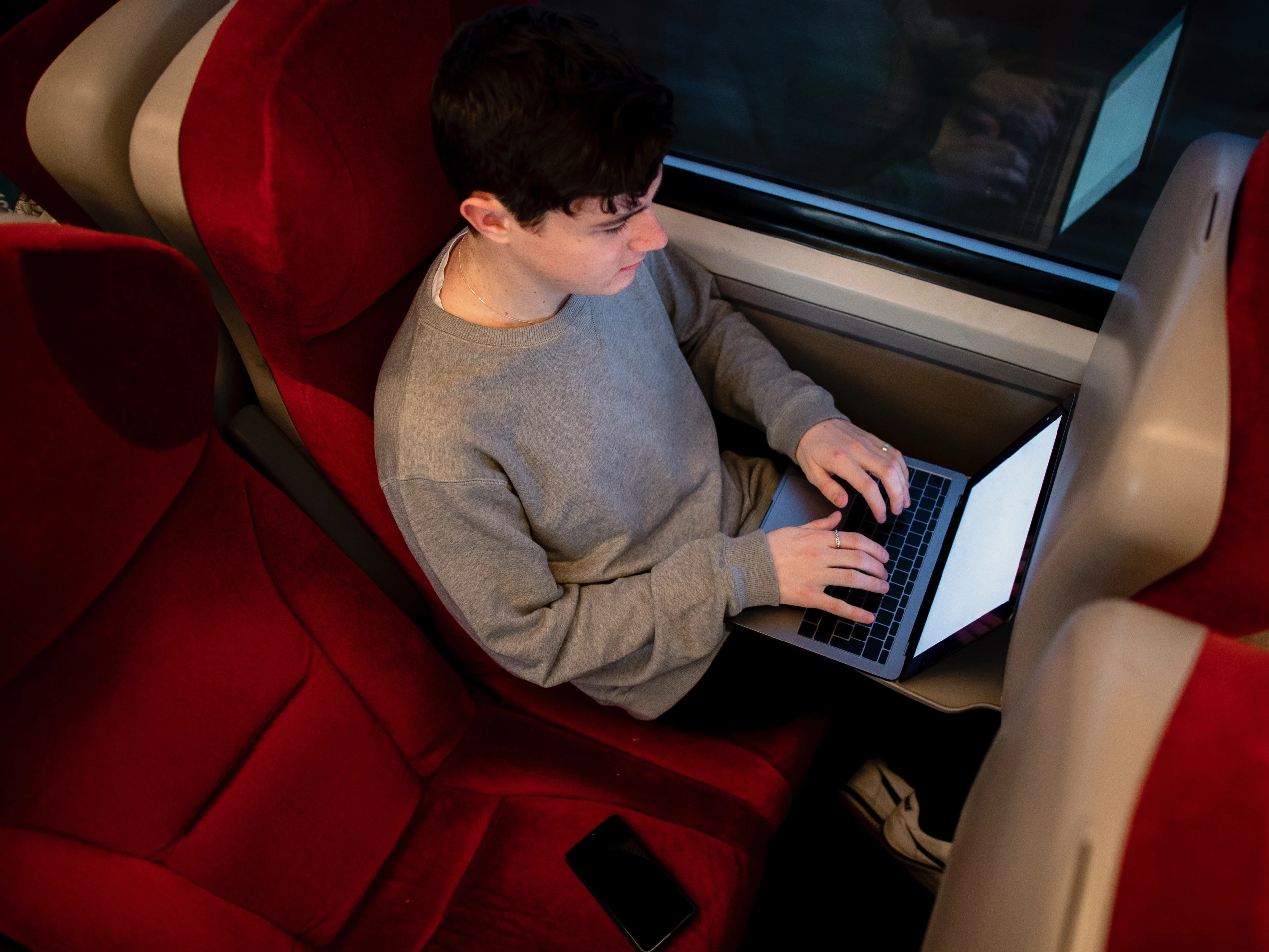 A young man working on his laptop on the train