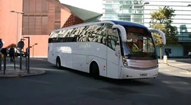A large white coach being driven on an empty urban road